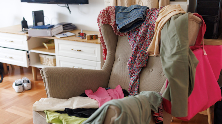 reading chair in a bedroom with clothing thrown on top