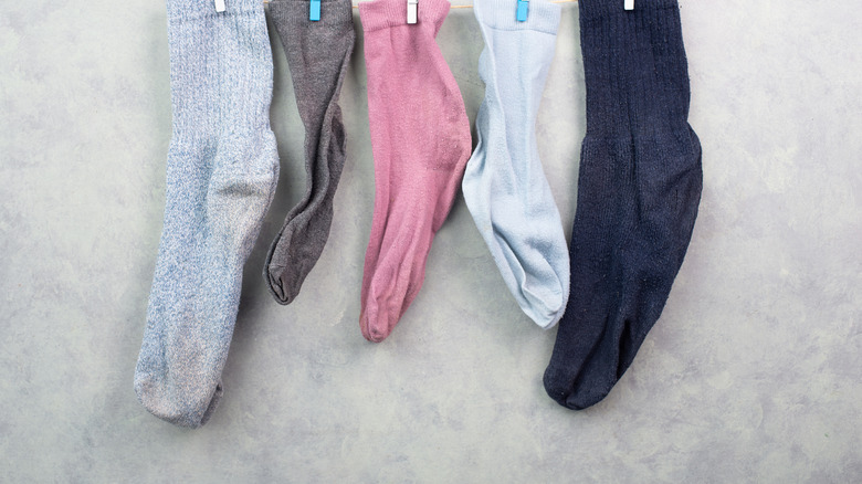 single socks hanging on a clothesline with white and blue clothespins