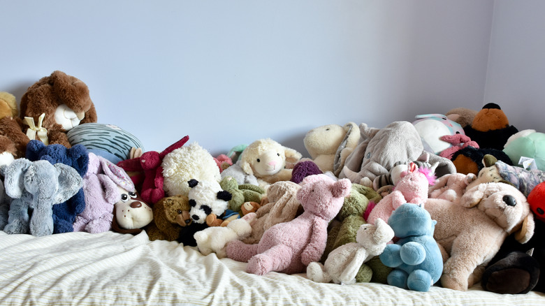 stuffed animals piled up on top of a bed