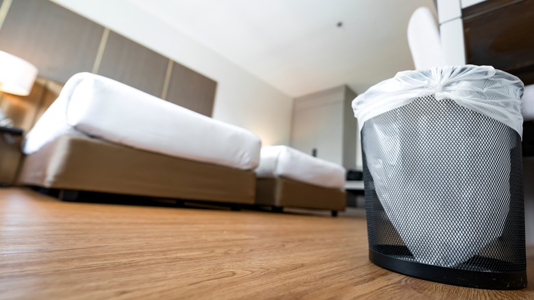 garbage can in a bedroom with clean wooden floors