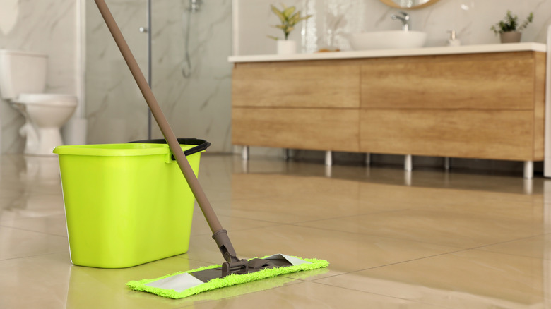 A bucket and dust mop in a bathroom