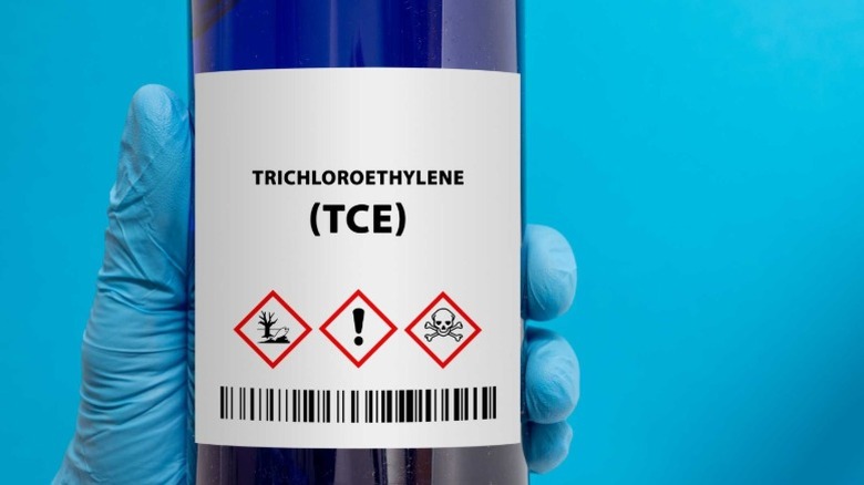 Gloved hand holding bottle of trichloroethylene