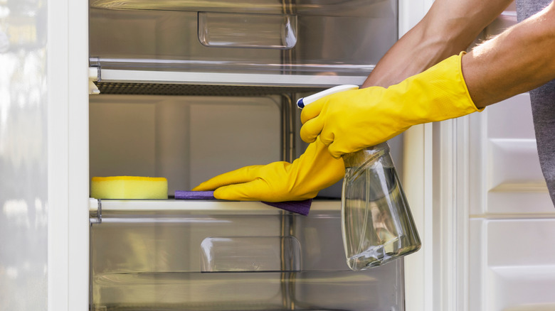 Someone cleaning the inside of a fridge