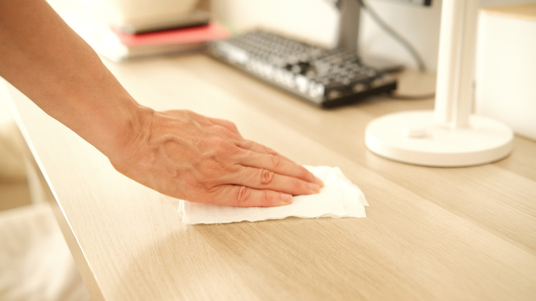 Using a cleaning wipe on a desk.