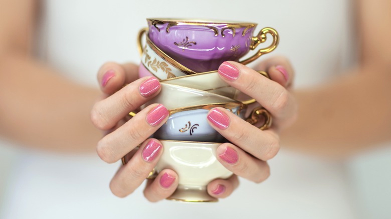 Person holding colorful vintage teacups in a stack