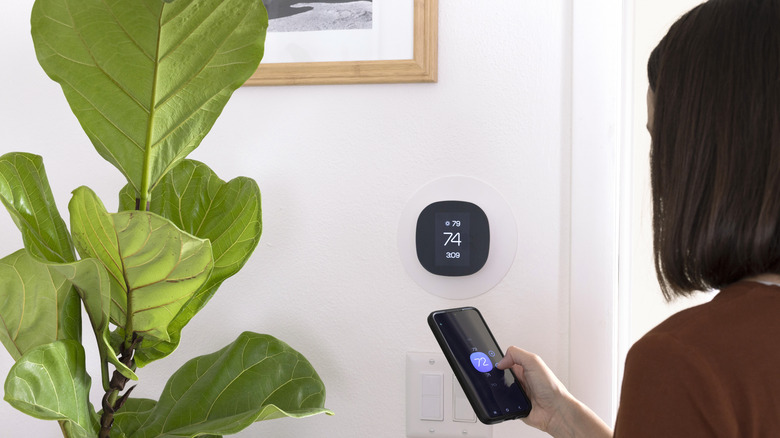 A person controlling their thermostat from their phone