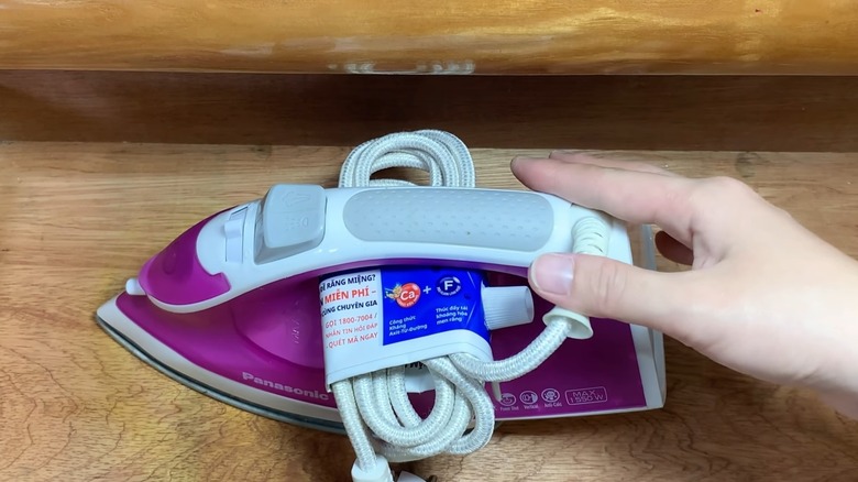 Woman organizing iron cord with toothpaste tube hack