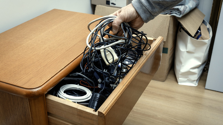 Man pulling tangled cords out of drawer