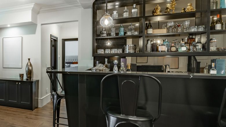 Home bar with bar stools and stocked shelves.