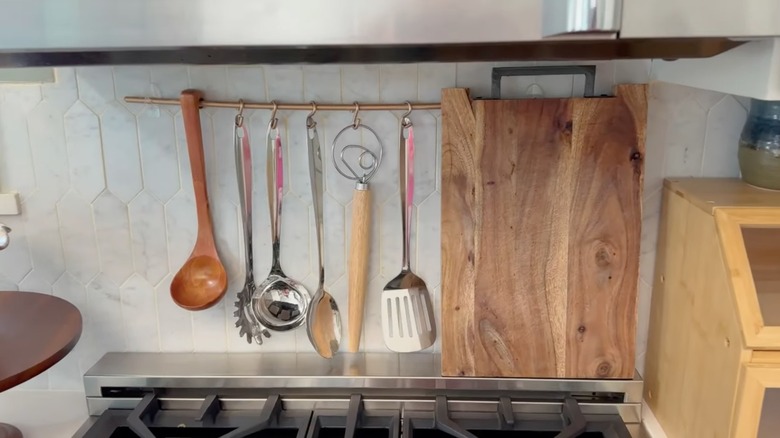 Cooking utensils hanging from storage rail on kitchen wall
