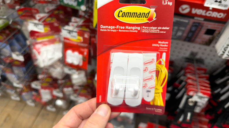 Person holding package of Command hooks in store
