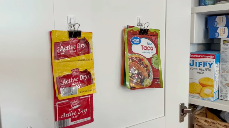 Command hooks and binder clips on spice packs for cabinet door storage