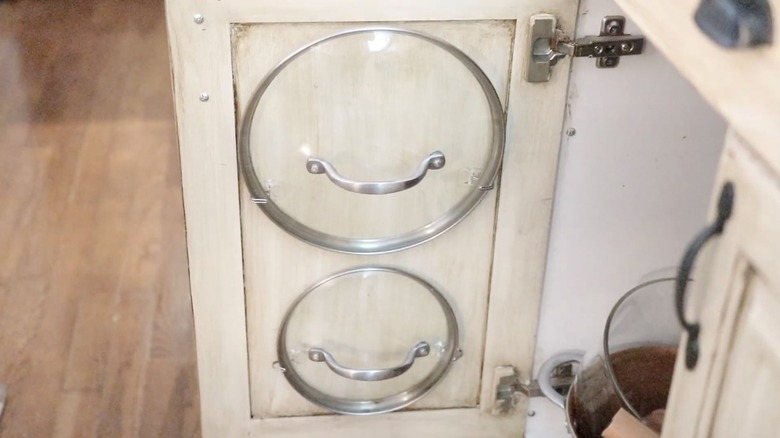 Pan lids stored on kitchen cabinet door using Command strips