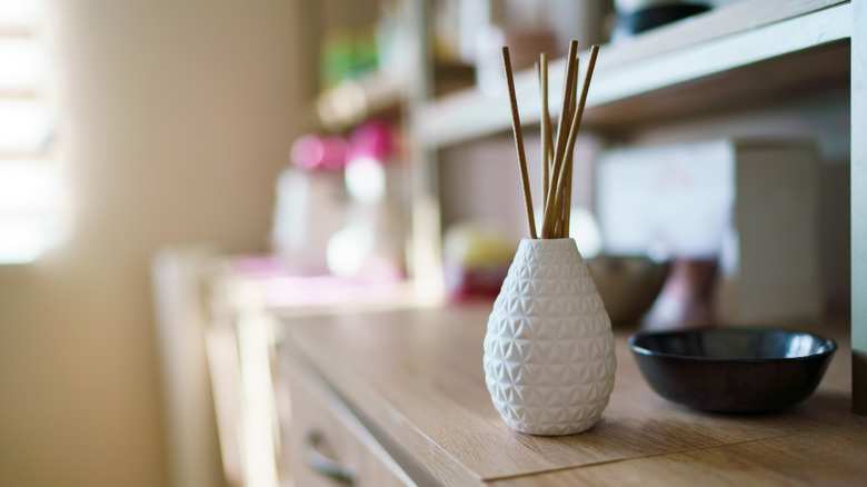 A white reed diffuser sits on a counter