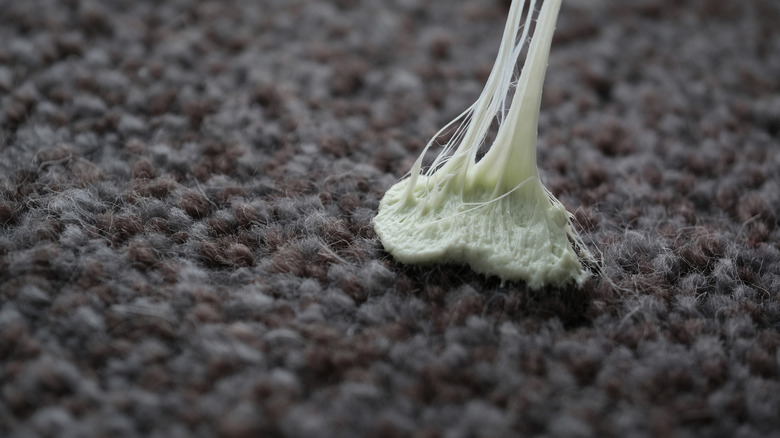 Gum being pulled off of gray carpet