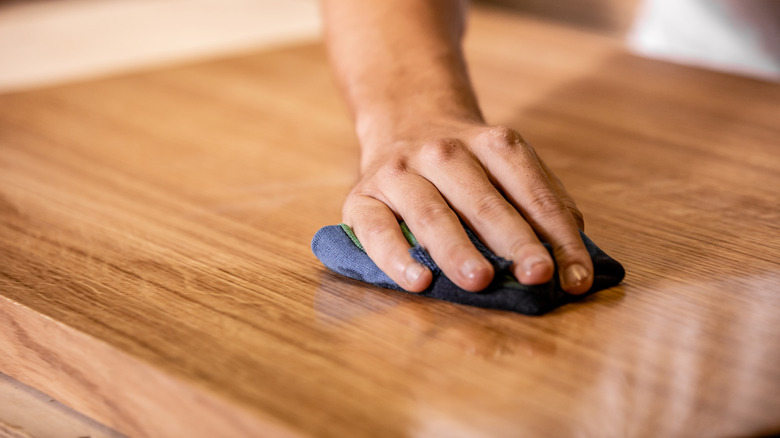 Hand polishing wood table top with oil