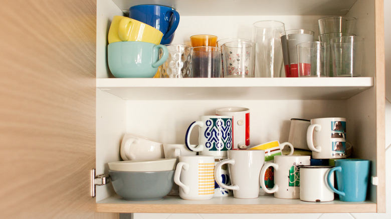 mugs stacked on top of each other on shelf inside cabinet