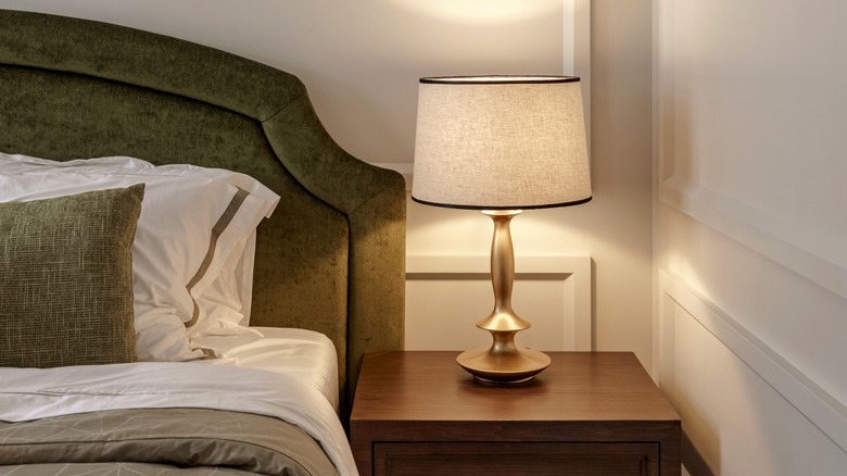 large upholstered green velvet bed with a wood nightstand that fills the entire space from bed to wall