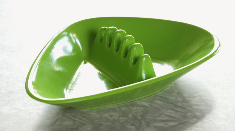 A retro green plastic ashtray sits on a metallic table