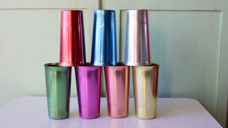 Colorful atomic aluminum cups are stacked on each other in front of a green wall