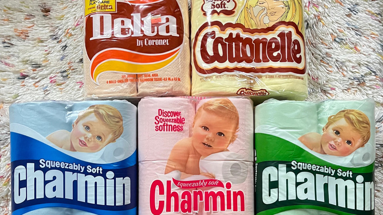 Five packs of vintage colored toilet paper are arranged on a shag carpet rug