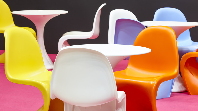 A collection of colorful vintage Panton chairs sit around three white tables