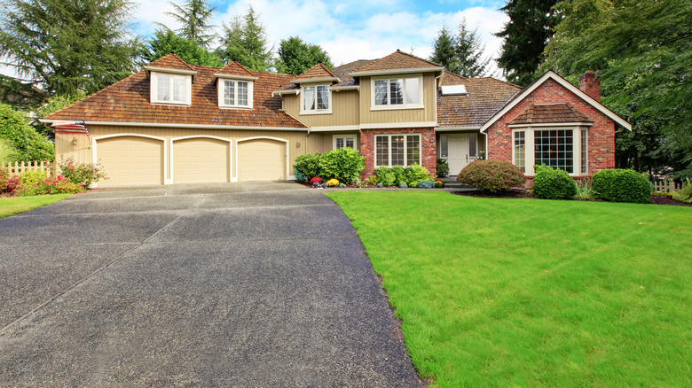 A large suburban home with a slightly aged asphalt driveway.