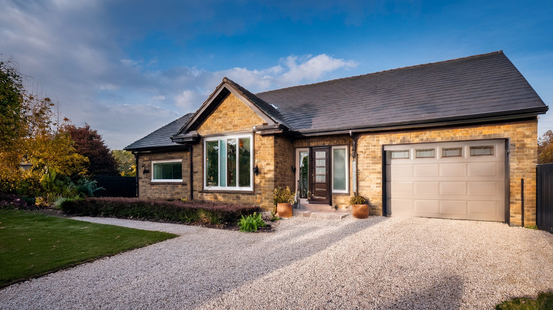 A brick suburban home with a well-maintained pea gravel driveway.
