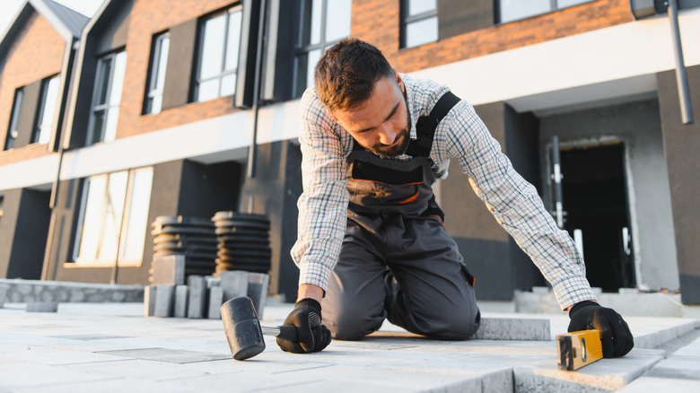 A construction worker installing a patio in front of a housing development
