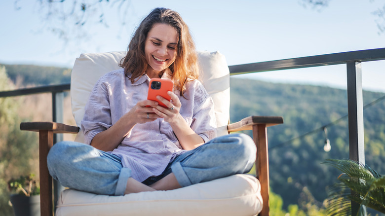 Woman smiling while sitting in her patio with her phone