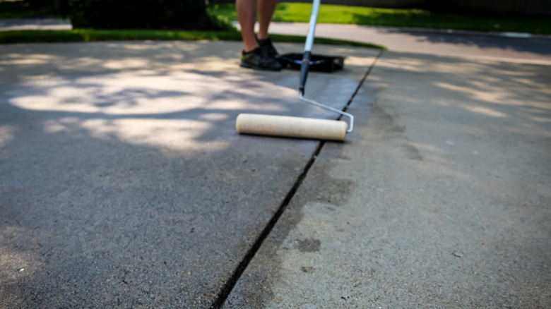 Homeowner sealing concrete driveway