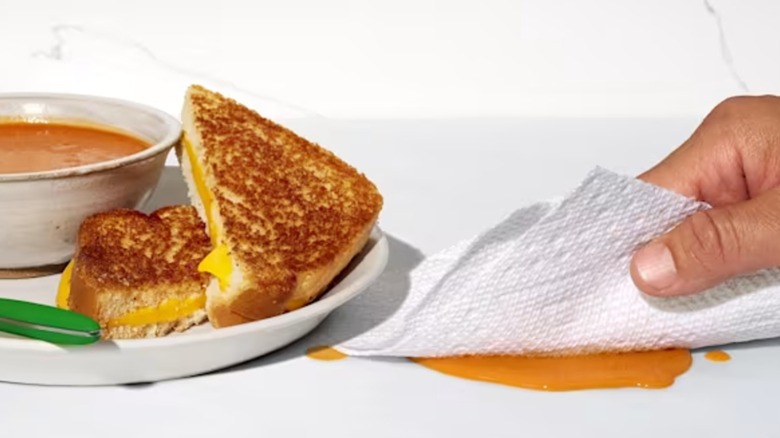 A hand cleaning up a soup spill with Bounty paper towel