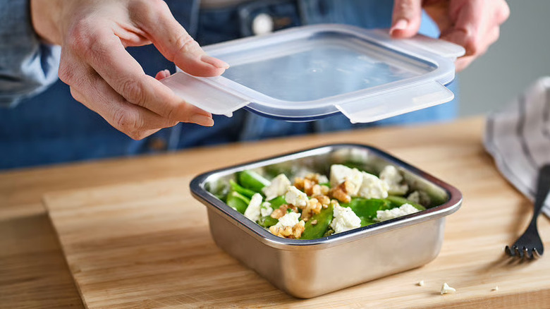 Person placing the lid on IKEA 365+ food container filled with salad