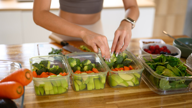 Closeup of a person placing freshly cut produce into food storage containers
