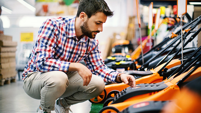 person looking at lawnmowers in store