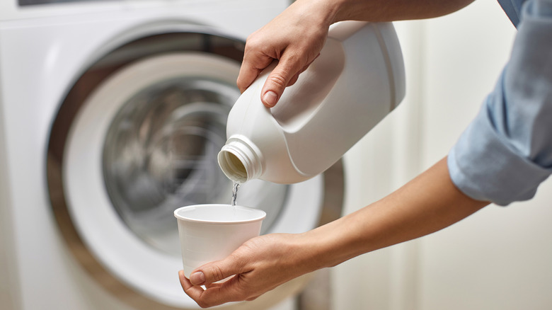 Pouring bleach into cup by washing machine