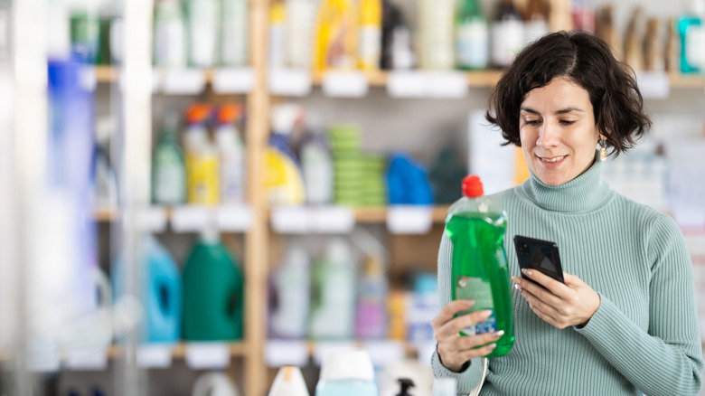A woman scanning QR code on a bottle of dishwashing detergent.