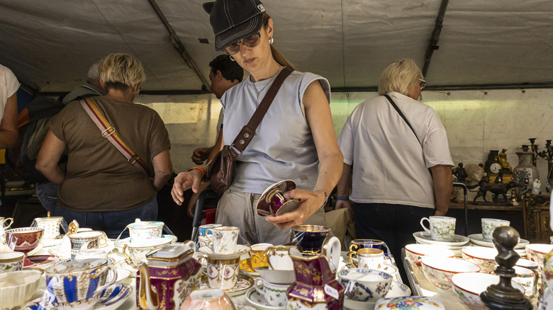 A person looks through a variety of antique dishes at a flea market