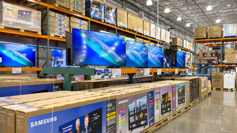 Aisles of a warehouse store linked with TVs on display and boxes of TVs for sale