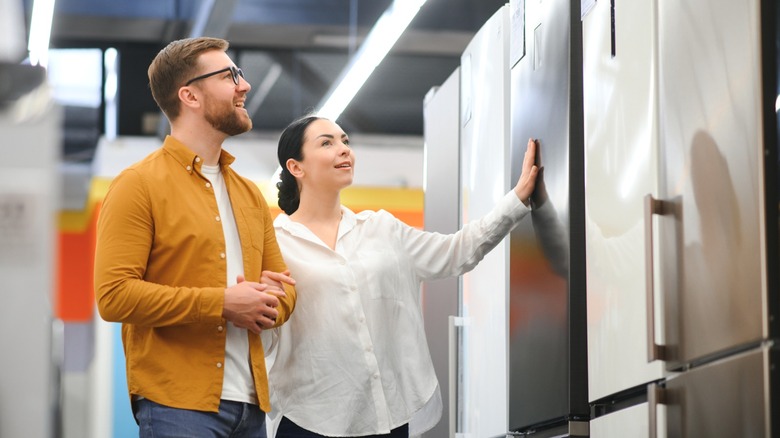 Couple shopping for refrigerators on a store showroom floor