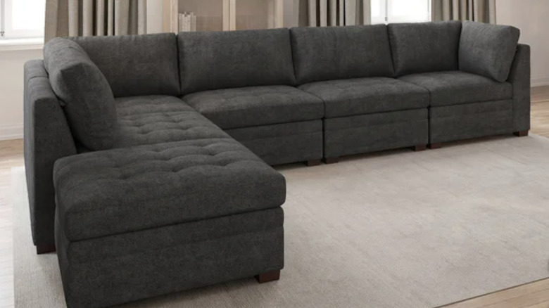 very large grey modular sectional in beige living room with six pieces including two end pieces and an ottoman