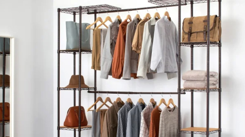 metal and wood closet organizer with clothes, bags, and hat in a closet or bedroom