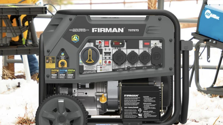 firman generator sitting outside in the snow with a man standing behind it