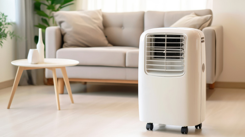 A white portable air conditioner unit sitting in a modern living room
