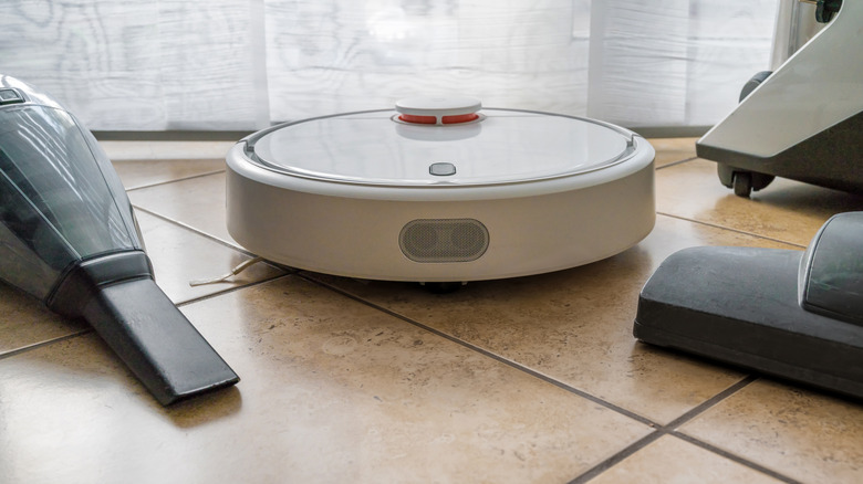 Three different types of vacuums sitting on a tile floor