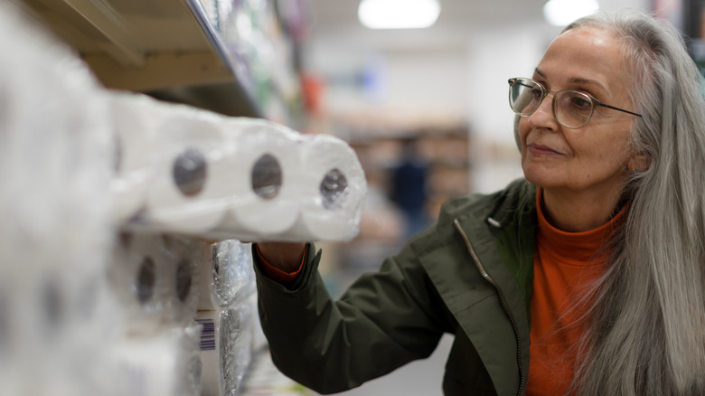 Senior woman buying toliet paper in supermarket
