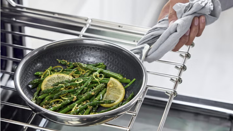 Someone pulling a Greenpan pan containing green beans out of the oven.