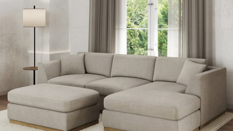 Henredon Caley Reversible Sofa in tan in a beige living room in front of window doors next to a floor lamp.