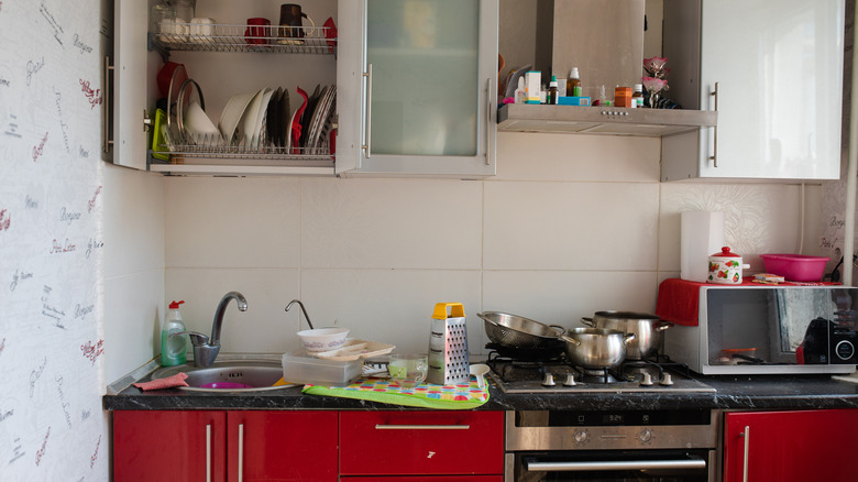 Bright but small kitchen with clutter on counter and cabinets