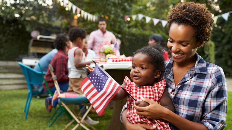 A woman holding a baby at a Fourth of July party
